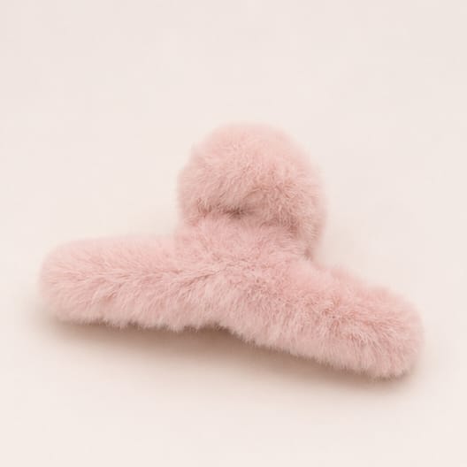 A light pink fluffy faux fur hair claw clip on a solid off-white background.