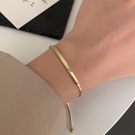 close up of gold adjustable bar bracelet showing smooth polished bar and sliding chain closure