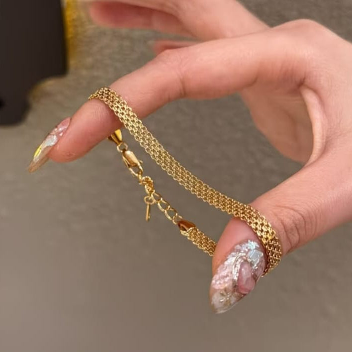 gold mesh chain bracelet with smooth woven texture and elegant minimal design on neutral background