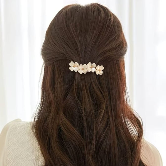 A brown wavy hair accessory with five cream flower-shaped beads and small pearl-like centers, shown clipped to the back of a woman's hair.
