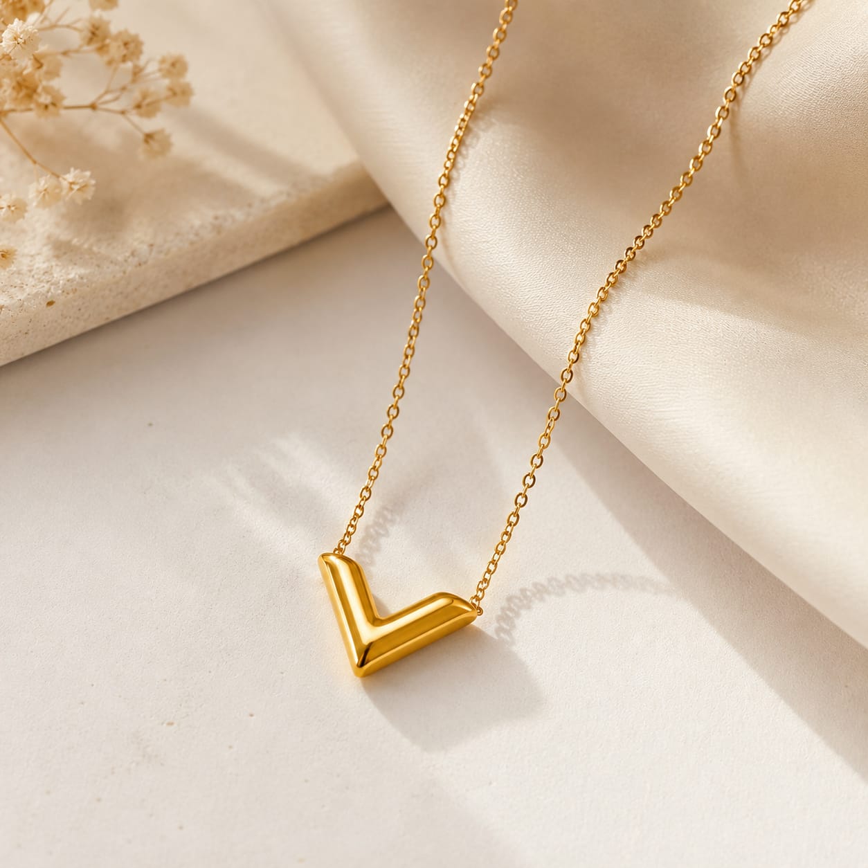 V pendant necklace placed on neutral background minimal aesthetic jewelry flat lay