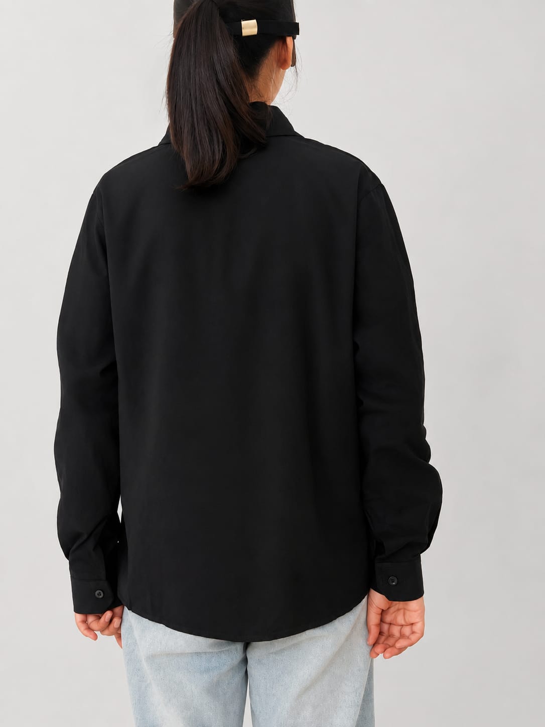 Model wearing black 100% cotton button-down shirt with a clean minimal modern style by NUR, suitable for smart casual and formal wear