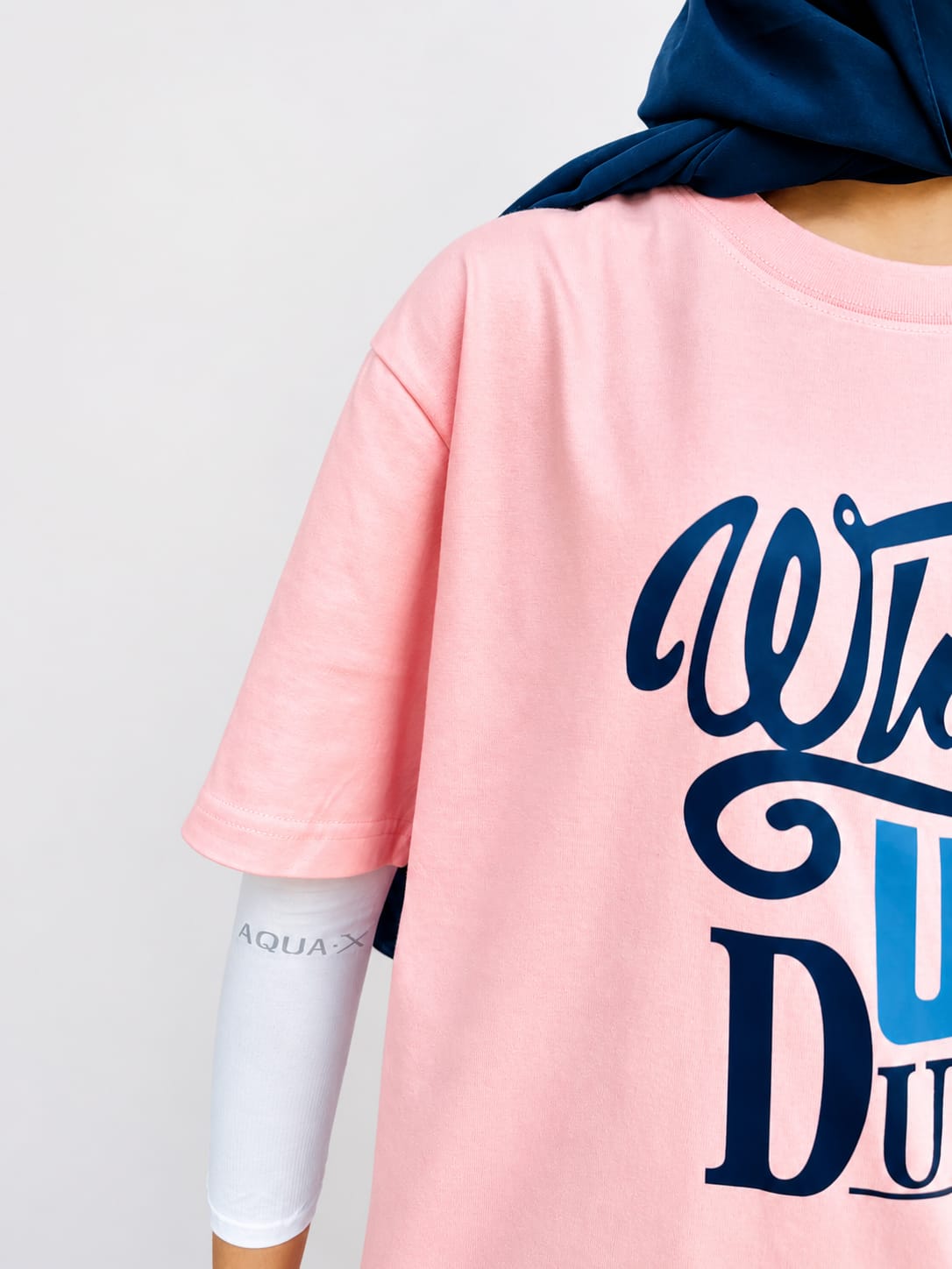 Model wearing pink graphic t-shirt with “Whats Up Dudes” print in a relaxed casual streetwear style by NUR