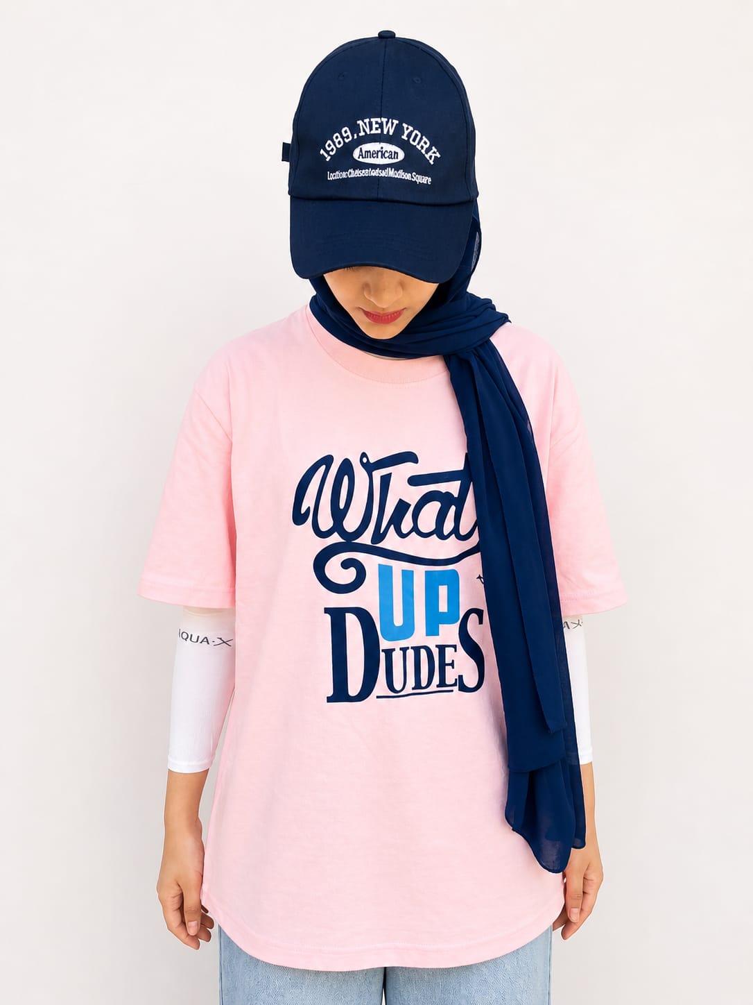 Model wearing pink graphic t-shirt with “Whats Up Dudes” print in a relaxed casual streetwear style by NUR